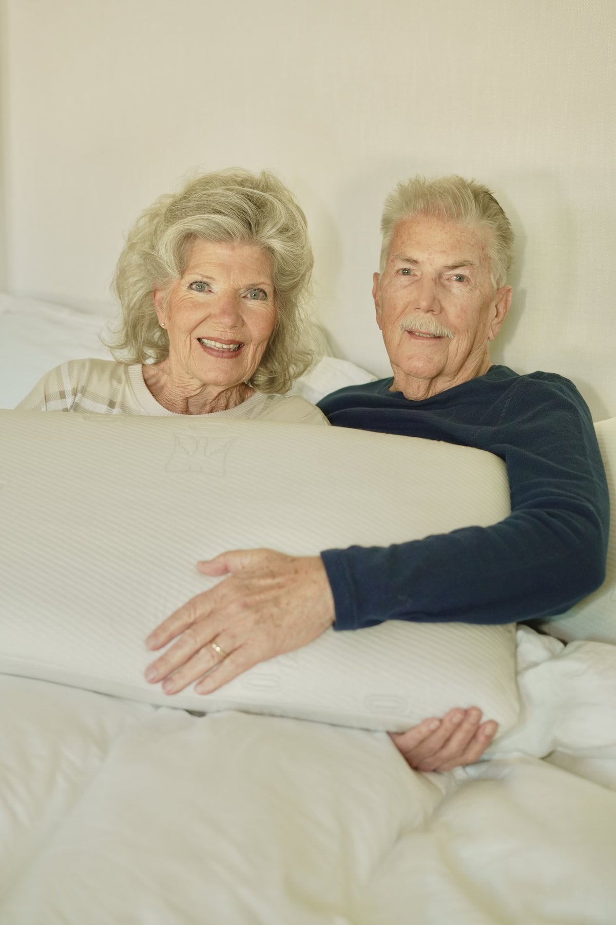 A couple resting in bed with an Angel Pillow